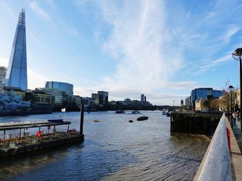 View of buildings by river against cloudy sky