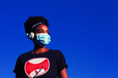 Portrait of young man standing against blue background