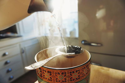 Close-up of water pouring on tea leaves in mug