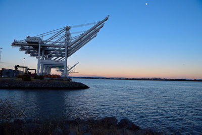 Cranes at commercial dock against clear sky