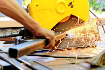 Close-up of worker using saw machine at industry