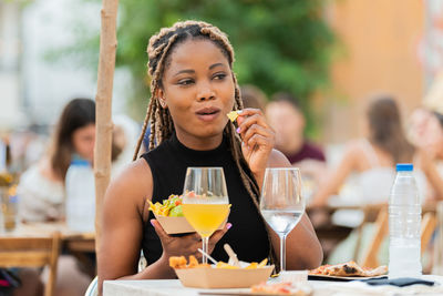 Smiling latina woman enjoying fast food and drinks at an outdoors terrace