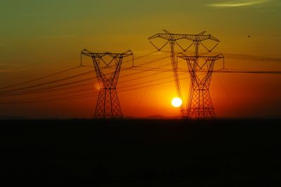 Silhouette electricity pylon against sky during sunset