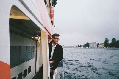 Young man looking away while standing against built structure