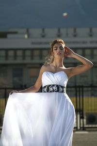 Portrait of beautiful woman standing against city in background