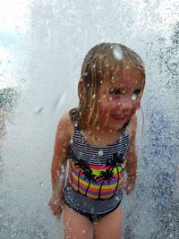 Cute little girl enjoying fountain during summer