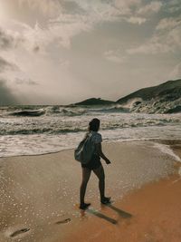 Rear view of full length of man standing on beach