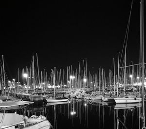 Boats moored in illuminated harbor against clear sky at night
