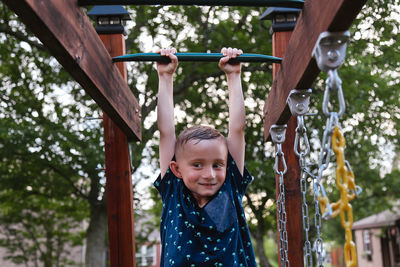 Smiling boy hanging on monkey bars