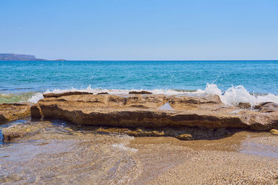 Rocks on beach against clear sky