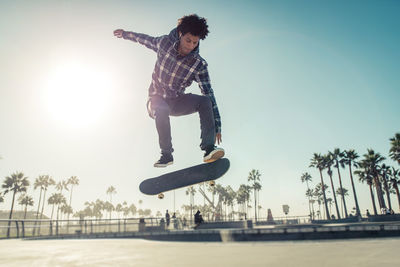 Full length of young man skateboarding on skateboard against sky