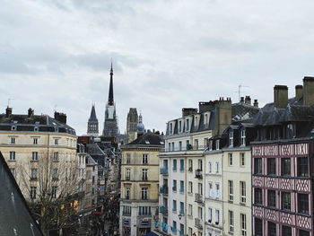 Buildings in city against cloudy sky