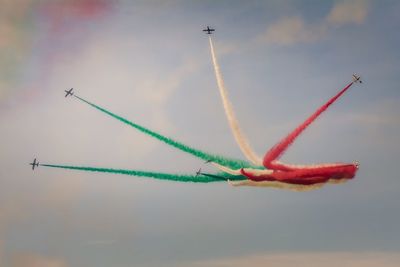 Low angle view of colorful airshow against sky