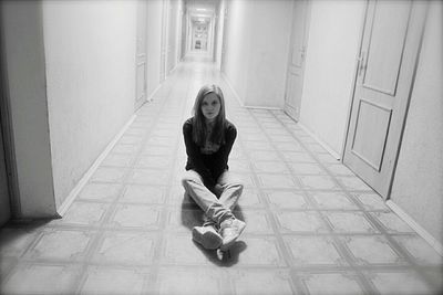 High angle view of sad woman sitting on corridor