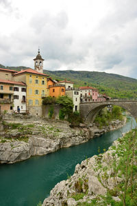 Buildings by river against sky