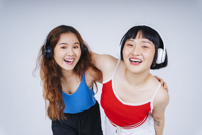 Lesbian couple listening music against gray background