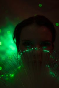 Portrait of beautiful young woman against illuminated background