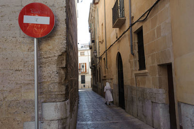 Rear view of woman walking in alley