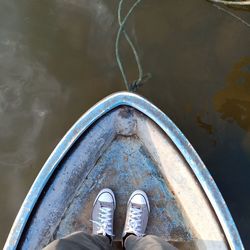 Low section of person standing in boat on lake