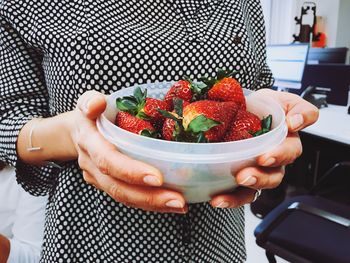 Midsection of woman holding bowl with strawberries