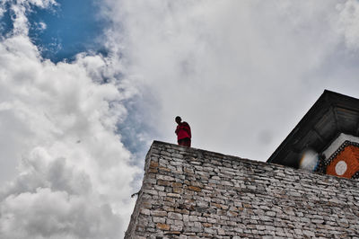 Low angle view of man standing by old building against sky