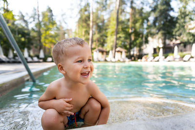 Smiling boy crouching in swimming pool