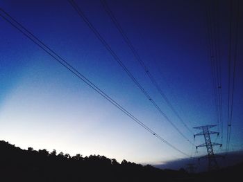 Low angle view of silhouette electricity pylon against clear sky