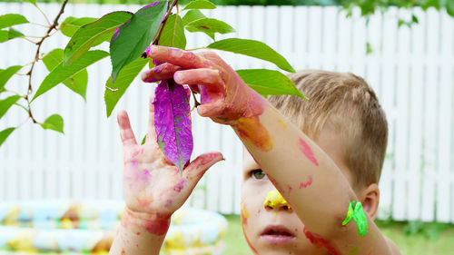 A little child, a four-year-old boy playing, painting with finger paints, decorating leaves on the