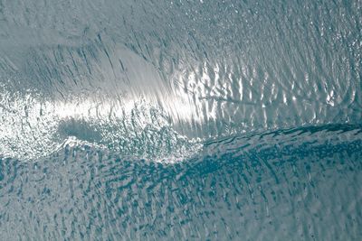 Silvery blue wake ripples across a wind-blown arctic ocean