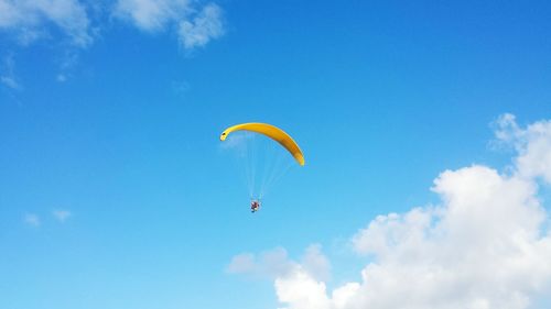 Low angle view of paragliding against blue sky