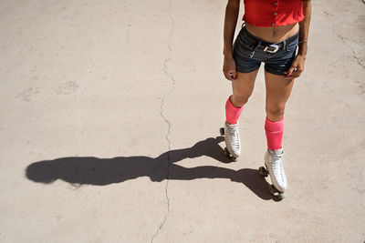 Concentrated female roller skating on sports ground on sunny day in city