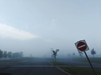 Road sign on street against sky