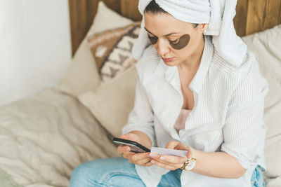 A woman holds a credit card and uses a laptop.