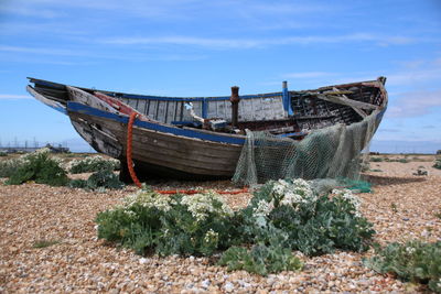 Fishing boat moored on beach against sky