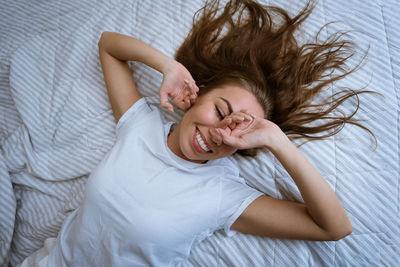 High angle view of cheerful woman lying on bed at home