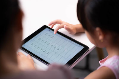 Cropped hands of woman using digital tablet while sitting on table