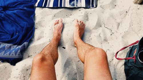 Low section of men sitting on sand