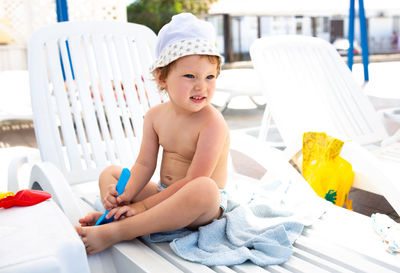 Small child in panama hat plays in the summer on sunny day near swimming pool