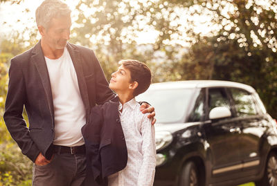 Smiling man looking at son against car on road