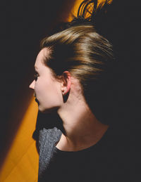 Portrait of young woman looking away against black background