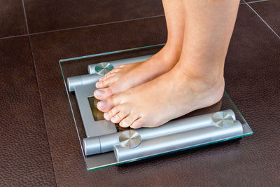 Low section of woman standing on tiled floor at home