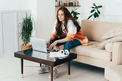 Long haired redhead modern young woman uses laptop for online business activities