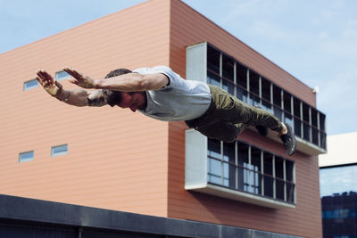 Athletic man doing parkour exercise outdoors jump with hands in the air person