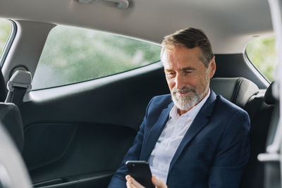 Rear view of man using mobile phone while sitting in car