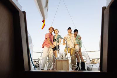 Happy couples standing by steering wheel on nautical vessel