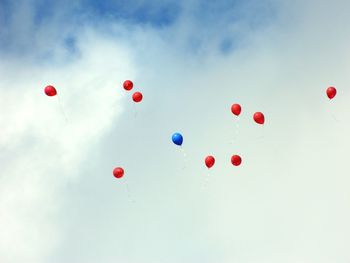 Low angle view of balloons flying in cloudy sky