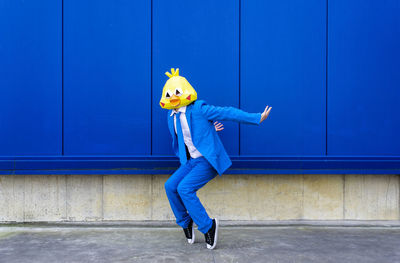 Full length of woman standing against yellow wall