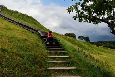 Boy sitting on steps at hill