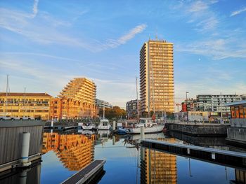 Buildings by river against sky in city