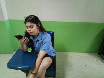 Young woman using mobile phone while sitting on seat